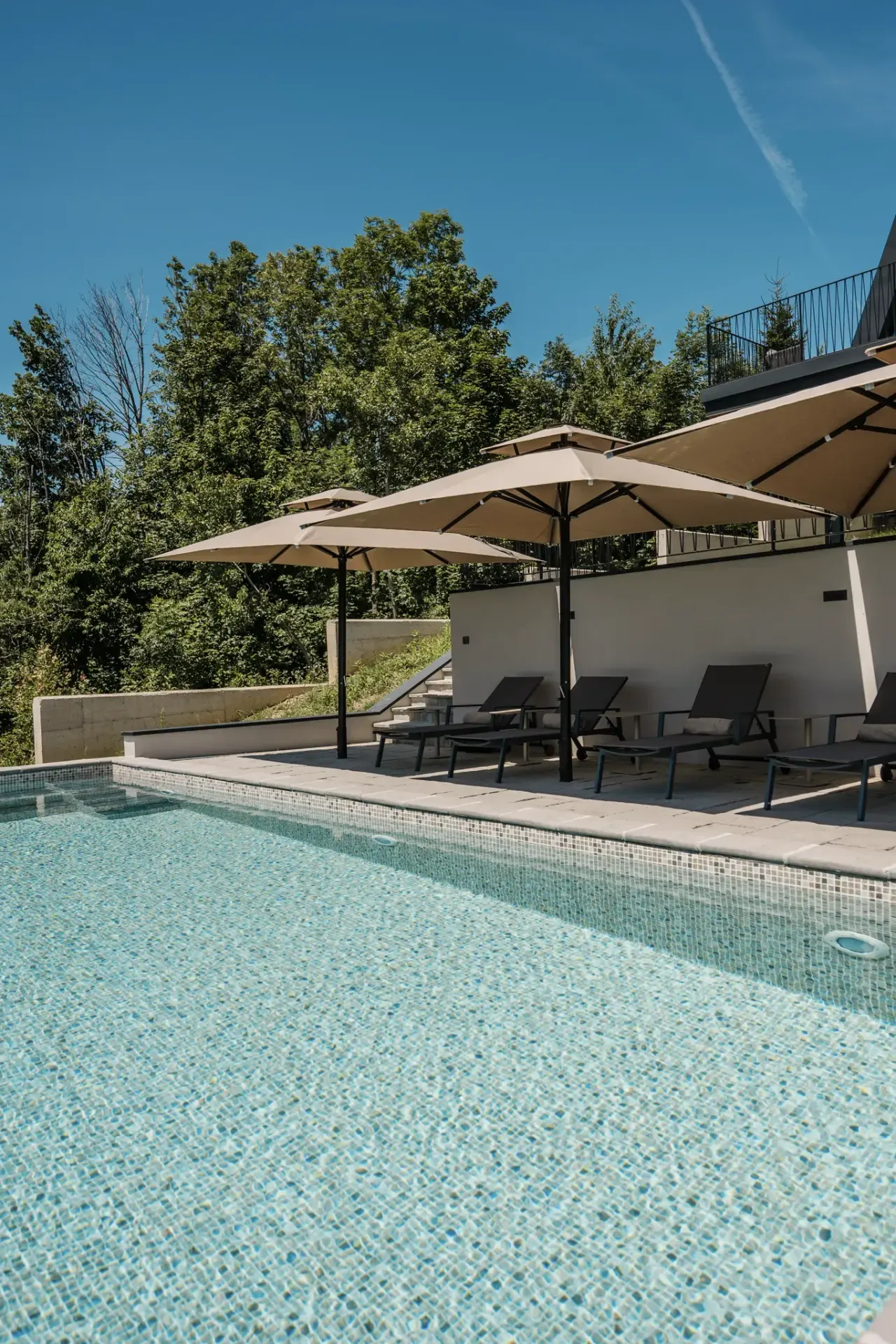 The heated pool under its parasols with sun loungers along the paving
