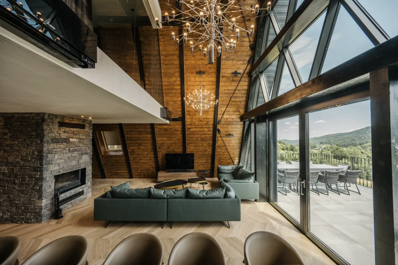 Double-height living room with the full glass gable and twin chandeliers by day
