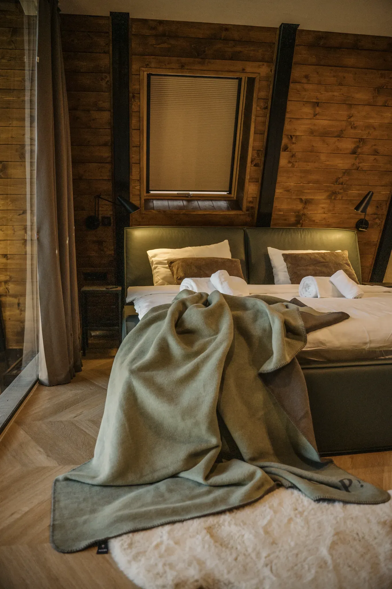 Master bedroom opening to the forest through a panoramic glass gable